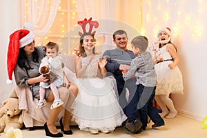 Happy big family portrait, celebrating new year or Christmas - parents and children in home interior decorated with holiday lights