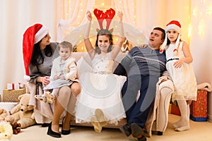 Happy big family portrait, celebrating new year or Christmas - parents and children in home interior decorated with holiday lights