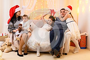Happy big family portrait, celebrating new year or Christmas - parents and children in home interior decorated with holiday lights