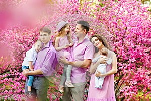 Happy big family of six are standing in spring park. Happy loving family concept. Happy family having fun on sakura garden