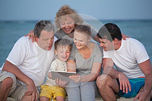 Happy big family with tablet PC on the beach