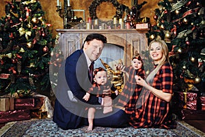 A happy big family with their children in the New Year& x27;s interior of the house by the fireplace next to the Christmas