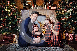 A happy big family with their children in the New Year's interior of the house by the fireplace next to the Christmas