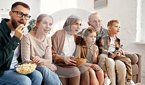 Happy big family watching TV and eating popcorn