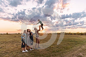 A happy big full family walks in a field in the summer.