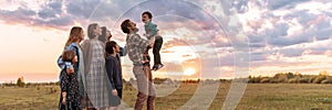 A happy big full family walks in a field in the summer.