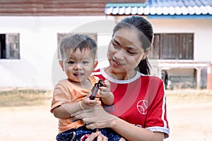 Happy big laughing child boy and young woman holding adorable baby boy outdoors at home.