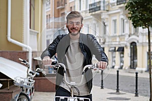 Happy bike messenger with backpack sits on bicycle and looks at the camera