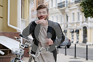 Happy bike messenger with backpack stands near bicycle and look at the camera