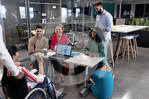 Happy biracial advisors listening to disabled businesswoman\'s strategy during meeting in boardroom