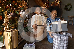 Happy biracial children unpack gifts on Christmas