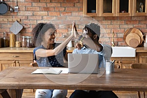 Happy biracial couple give high five celebrate success at home