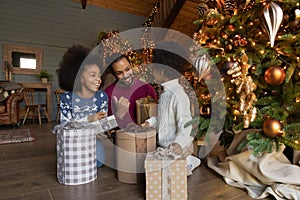 Happy biracial dad and kids unpack Christmas gifts together