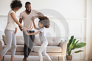 Happy biracial family with kid dancing at home