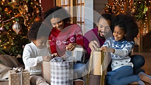 Happy biracial family with kids open Christmas presents