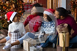 Happy biracial family with kids unpack Christmas presents