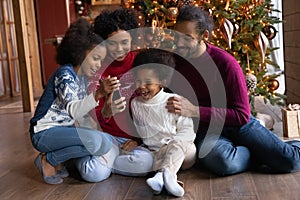 Happy biracial family with kids use cellphone at home