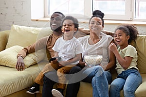 Happy biracial family with kids watching TV together