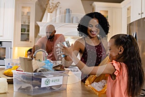 Happy biracial family sorting rubbish for recycling on kitchen counter