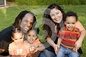 Happy biracial family with triplets at a park.