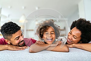 Happy biracial girl smiling with young multiracial parents enjoy weekend at home together,