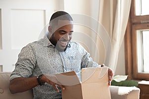 Happy biracial man feel excited unpacking delivery package