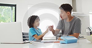 Happy biracial man and his son doing homework together, highfiving