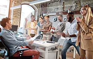 Happy birthday from all of us. Mixed race happy young coworkers celebrating a birthday of colleague in the modern office