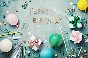 Happy birthday background or greeting flyer. Colorful holiday supplies on blue vintage table top view. Flat lay style.