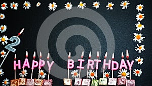 Happy birthday background with number 2. Copy space. Pink happy birthday candles on a black background. Happy birthday flower fra