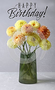 Happy Birthday! Beautiful yellow dahlia flowers in vase on table against grey background