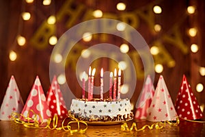 Happy birthday cake with candles on the background of garlands a