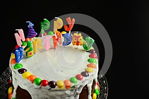 Happy birthday cake with candles on black background