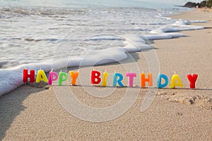 Happy birthday candles on a beach