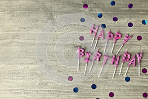 Happy birthday candles and glitter on gray wooden background