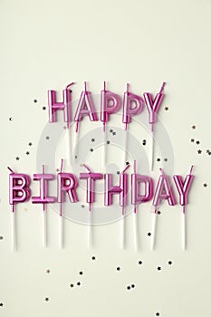 Happy birthday candles and glitter on white background