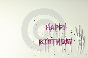 Happy birthday candles and glitter on white background