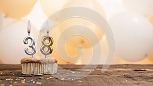 Happy birthday card with candle number 38 in a cupcake against the background of balloons. Copy space happy birthday for thirty