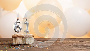 Happy birthday card with candle number 61 in a cupcake against the background of balloons. Copy space happy birthday for sixty one