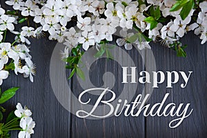 Happy birthday card with flowers. Spring card with blooming cherry on a gray wooden background. View from above