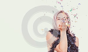 Happy birthday concept, young blond woman blowing festive confetti