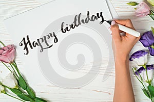 Happy birthday congratulations. Calligrapher writes with black ink on white card. Calligraphy. Ornament font. The art of photo
