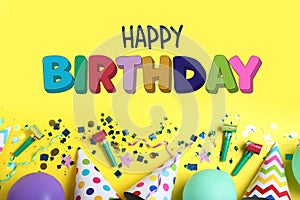 Happy Birthday! Flat lay composition with party hats, balloons and confetti on yellow background