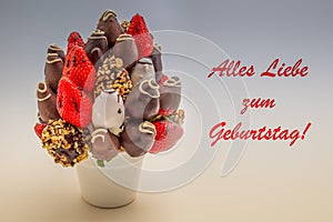 Happy birthday greeting card in German that reads Alles Liebe zum Geburtstag with red lettering; A bundle of edible flowers,