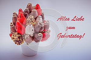 Happy birthday greeting card in German that reads Alles Liebe zum Geburtstag with red lettering; A bundle of edible flowers,