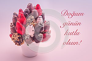Happy birthday greeting card that reads Dogum gunun kutlu olsun with red lettering; A bundle of edible flowers, arrangement of