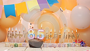 Happy birthday greetings for 85 years from gold letters of candles burning against the background of mine space balloons.
