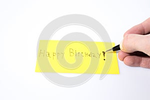 Happy birthday handwrite with a pen and a hand on a yellow paper