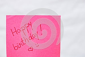 Happy birthday handwriting text close up isolated on pink paper with copy space. Writing text on memo post reminder