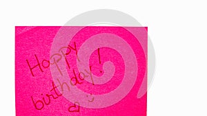 Happy birthday handwriting text close up isolated on pink paper with copy space. Writing text on memo post reminder